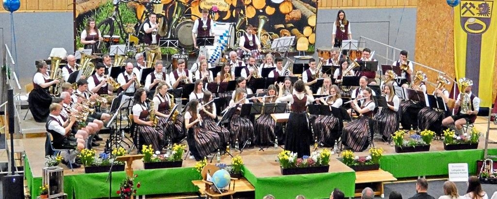 Die Musikkapelle Thundorf-Straß auf der Bühne mit Blumenschmuck und – passend zum Motto – Globus sowie Atlas. Image